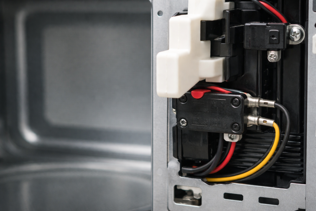 Microwave door latch pressing the door switch inside the appliance frame.